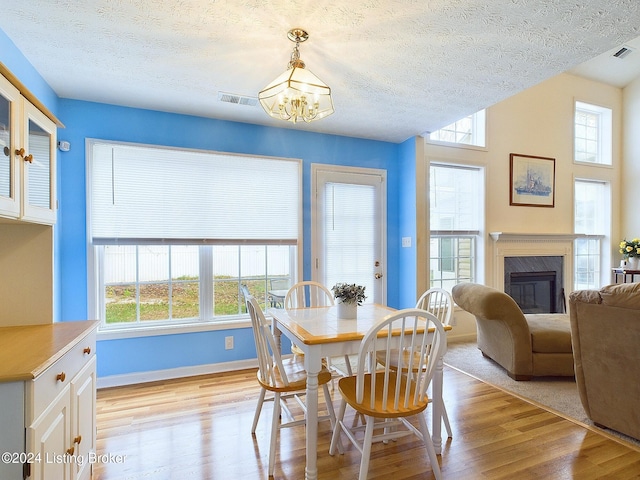 dining room featuring a wealth of natural light, an inviting chandelier, a high end fireplace, and light hardwood / wood-style flooring