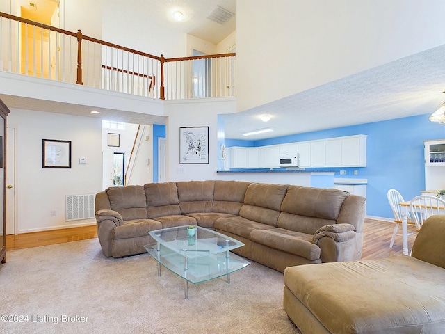 living room featuring light hardwood / wood-style flooring, high vaulted ceiling, and a textured ceiling