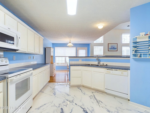 kitchen featuring a textured ceiling, white cabinetry, white appliances, and sink