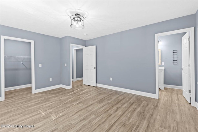 unfurnished bedroom featuring connected bathroom, a closet, and light hardwood / wood-style flooring