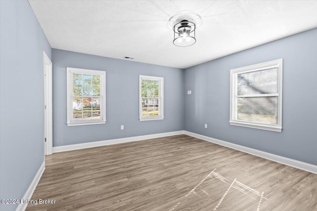 unfurnished room featuring wood-type flooring and a textured ceiling