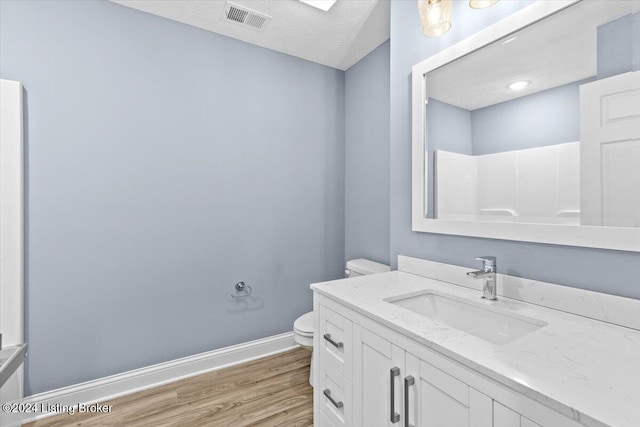 bathroom featuring toilet, hardwood / wood-style floors, a textured ceiling, vanity, and a shower