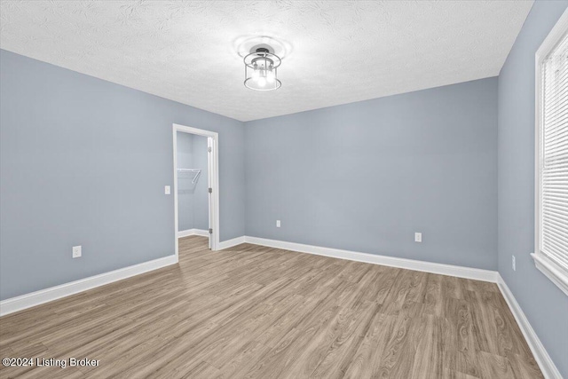 empty room featuring a textured ceiling and light hardwood / wood-style flooring