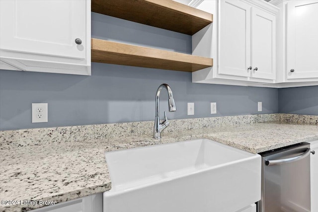 room details featuring white cabinets, stainless steel dishwasher, sink, and light stone counters