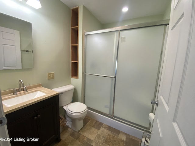 bathroom featuring vanity, toilet, and a shower with shower door