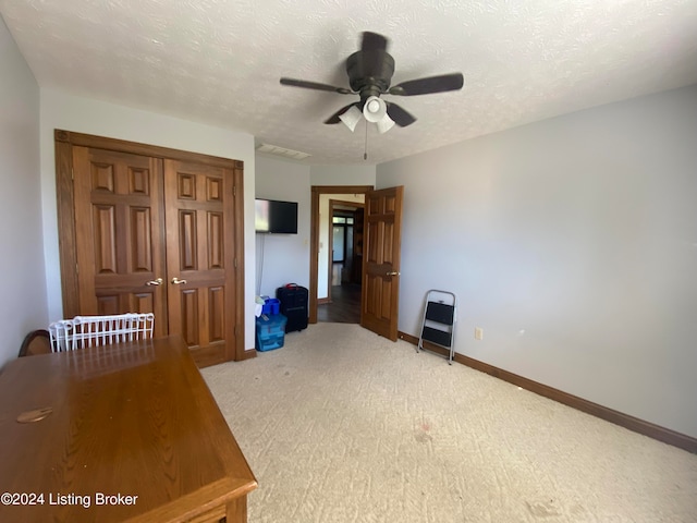 unfurnished bedroom with ceiling fan, light carpet, a closet, and a textured ceiling