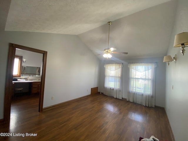 interior space with ceiling fan, dark hardwood / wood-style flooring, vaulted ceiling, and a textured ceiling