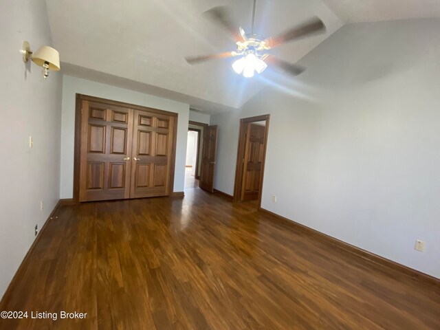 unfurnished bedroom with ceiling fan, lofted ceiling, dark hardwood / wood-style flooring, and a closet