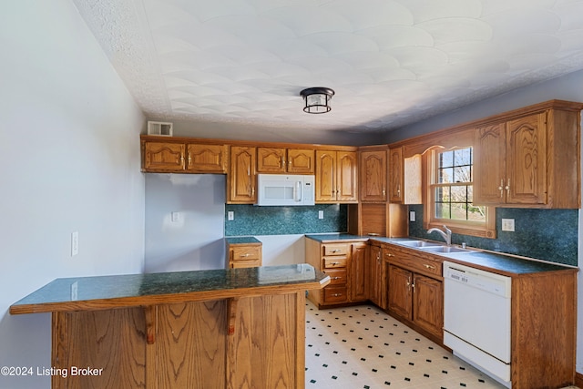 kitchen with backsplash, white appliances, and sink