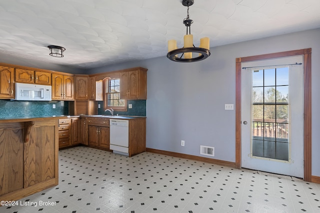 kitchen with backsplash, white appliances, a healthy amount of sunlight, and pendant lighting