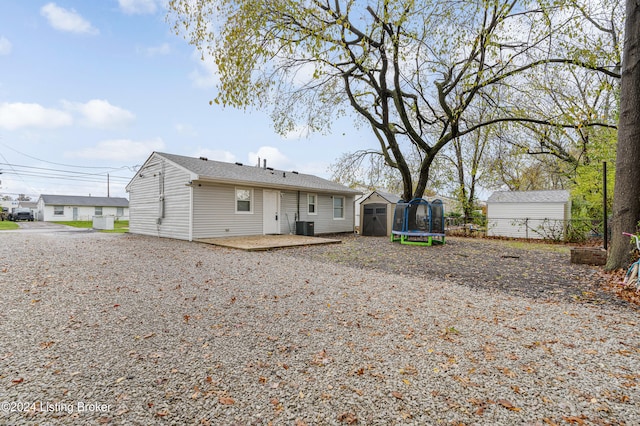 rear view of property with central AC unit, a shed, a trampoline, and a patio