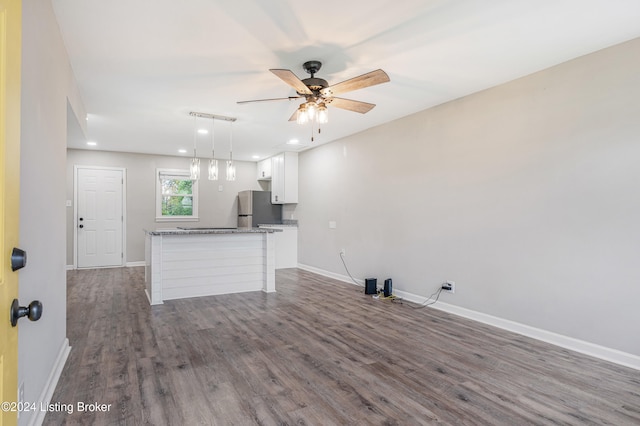 kitchen with stainless steel refrigerator, light stone countertops, dark hardwood / wood-style floors, decorative light fixtures, and white cabinets