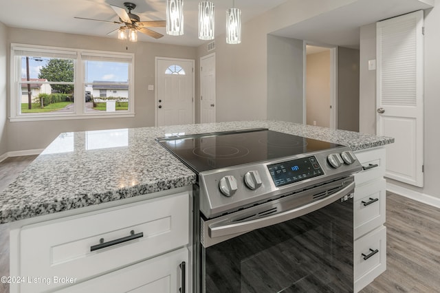 kitchen featuring light stone countertops, a center island, light hardwood / wood-style flooring, electric stove, and white cabinets