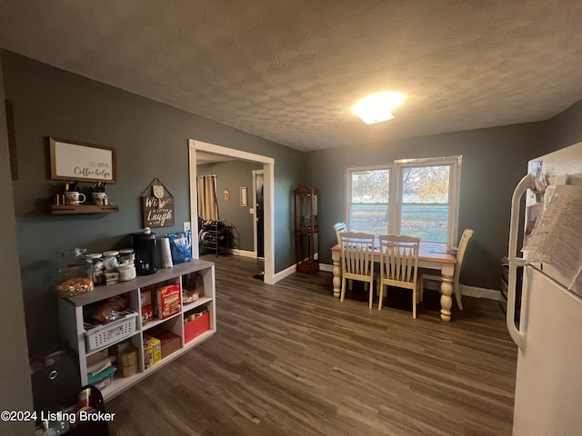 dining area featuring dark wood-type flooring and a textured ceiling