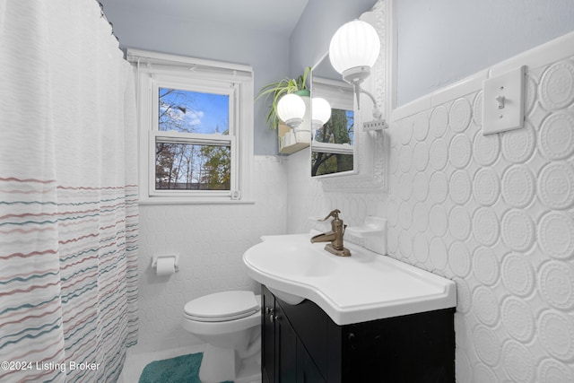 bathroom with tile patterned flooring, vanity, toilet, and tile walls