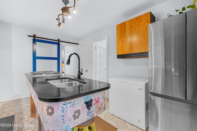 kitchen with a center island with sink, sink, stainless steel fridge, a barn door, and fridge