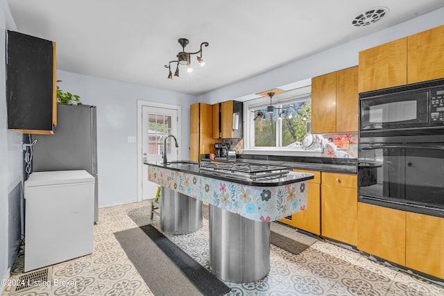 kitchen featuring sink, a center island, backsplash, a breakfast bar, and black appliances