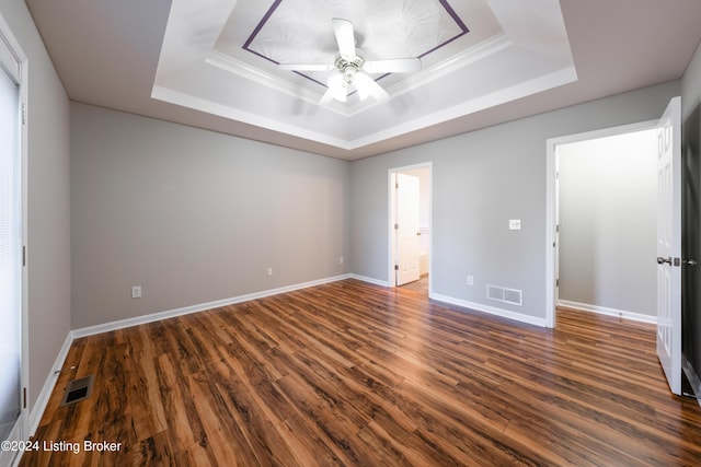 unfurnished bedroom featuring a raised ceiling, ceiling fan, and dark hardwood / wood-style flooring