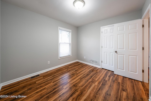 unfurnished bedroom with dark hardwood / wood-style floors and a closet