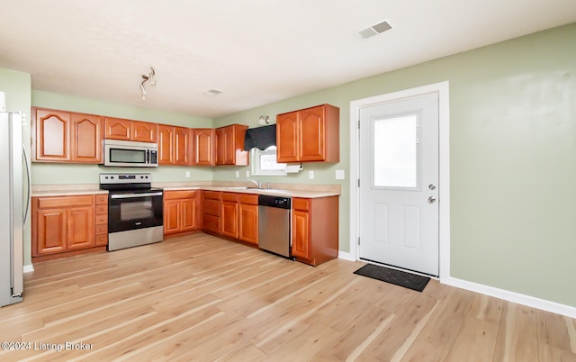 kitchen featuring light wood-type flooring, sink, and appliances with stainless steel finishes