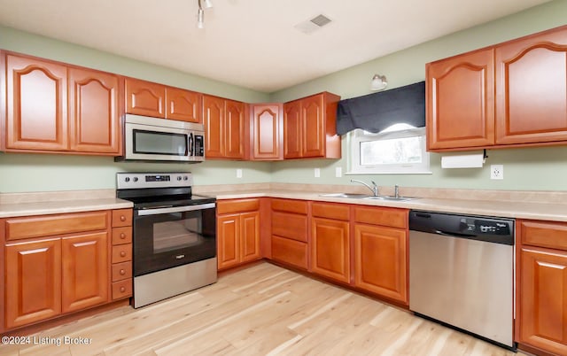 kitchen with light hardwood / wood-style floors, sink, and appliances with stainless steel finishes