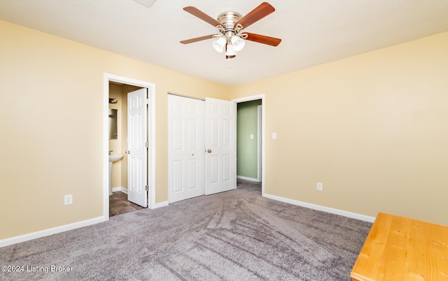 unfurnished bedroom featuring a closet, ceiling fan, ensuite bathroom, and dark carpet