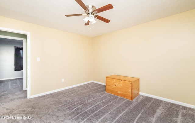 spare room with ceiling fan and dark colored carpet