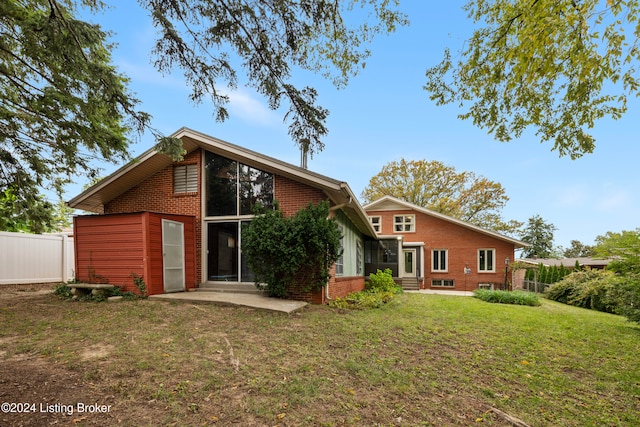 back of house with a patio area and a lawn