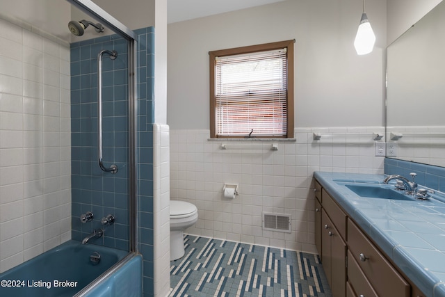 full bathroom featuring vanity, tiled shower / bath combo, tile walls, tile patterned flooring, and toilet