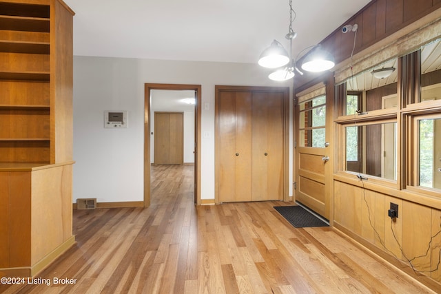 unfurnished dining area with light hardwood / wood-style floors and a notable chandelier