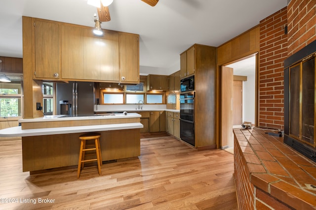 kitchen with kitchen peninsula, ceiling fan, light hardwood / wood-style flooring, and black appliances