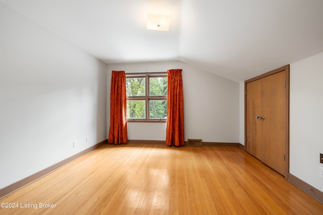 bonus room with light hardwood / wood-style floors and vaulted ceiling