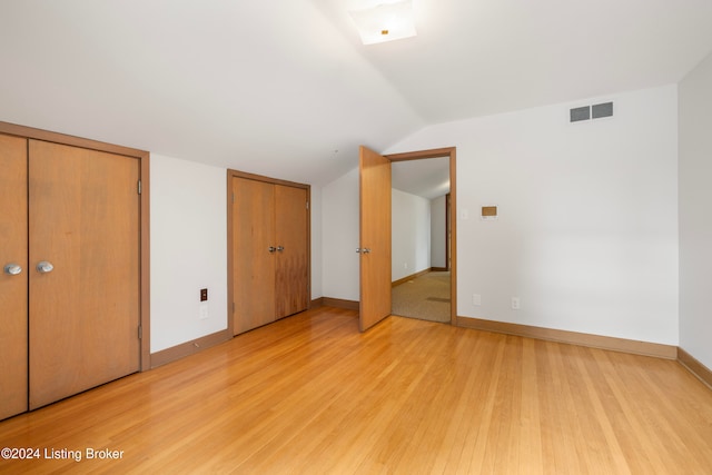 unfurnished bedroom featuring light hardwood / wood-style floors and lofted ceiling