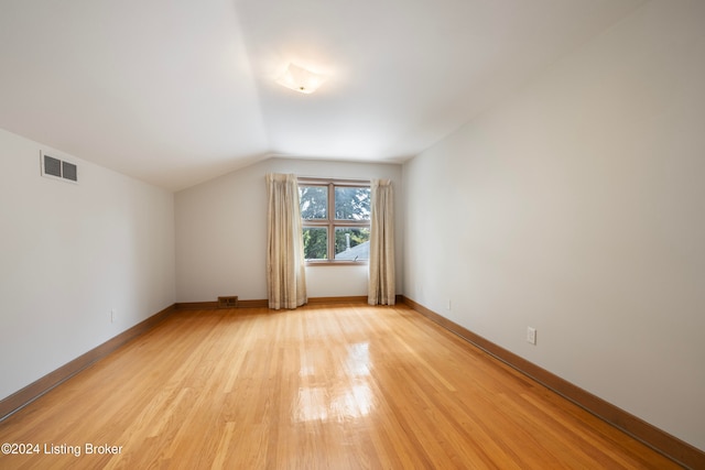 additional living space with light hardwood / wood-style flooring and lofted ceiling