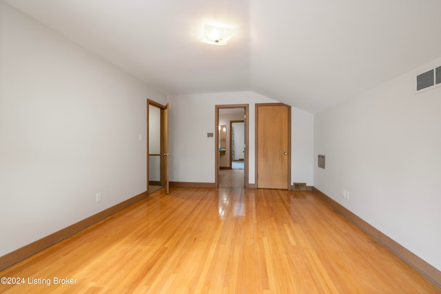 additional living space with hardwood / wood-style floors and vaulted ceiling