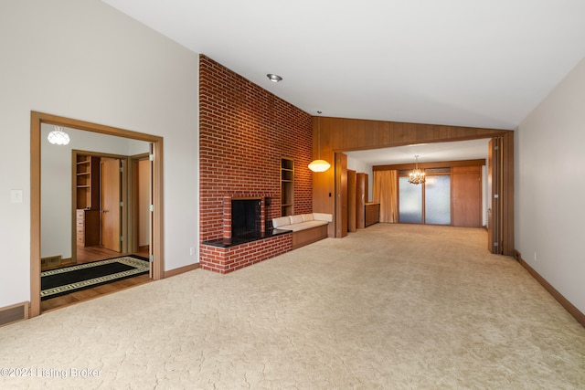 unfurnished living room with light carpet, an inviting chandelier, lofted ceiling, and a brick fireplace