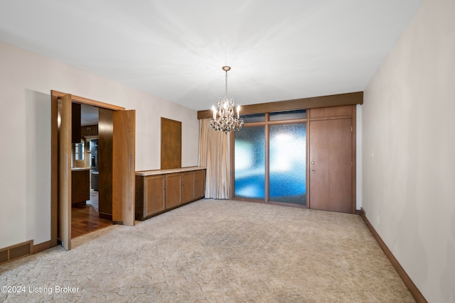 carpeted spare room with an inviting chandelier