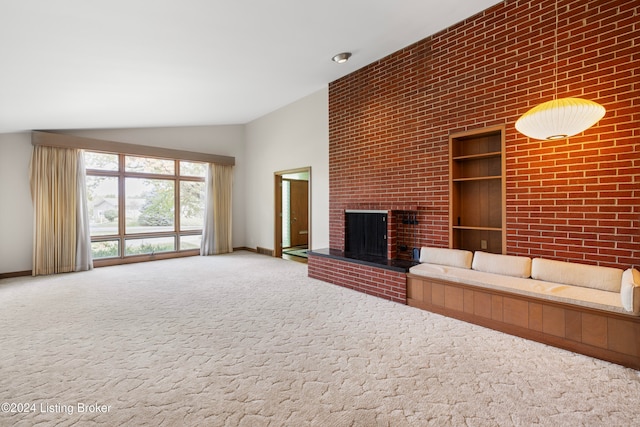 unfurnished living room with carpet floors, a fireplace, brick wall, and vaulted ceiling