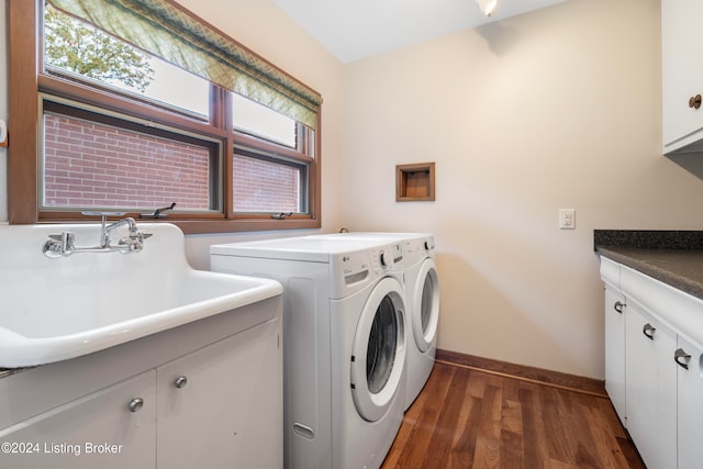 laundry room with washing machine and dryer, sink, cabinets, and dark hardwood / wood-style floors