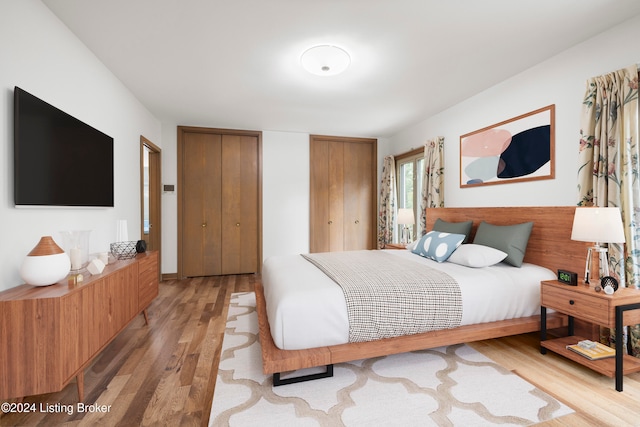 bedroom featuring light hardwood / wood-style floors and two closets