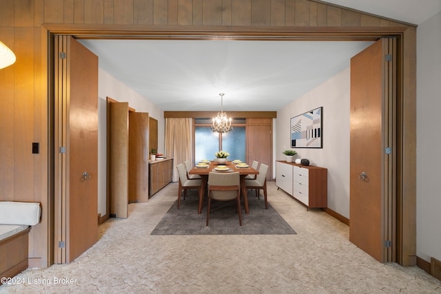 dining space featuring wood walls, lofted ceiling, and a notable chandelier