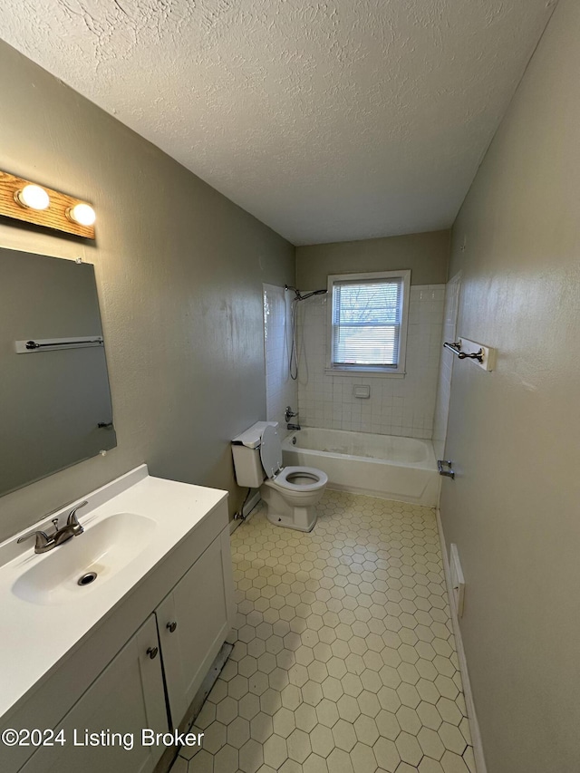 full bathroom featuring vanity, a textured ceiling, toilet, and tiled shower / bath