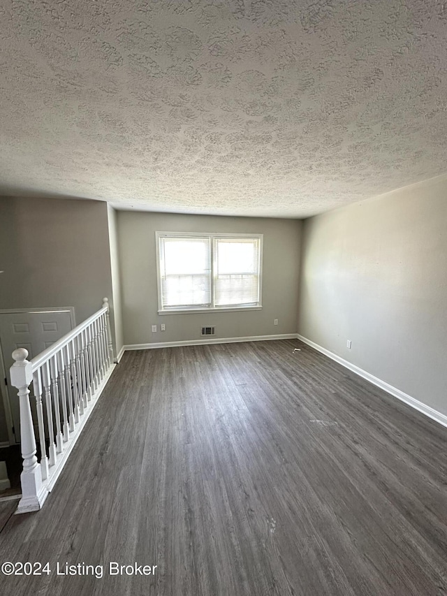 empty room with dark hardwood / wood-style flooring and a textured ceiling