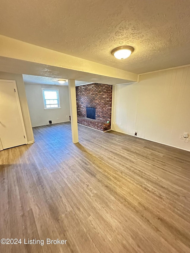 basement featuring a textured ceiling, wood-type flooring, and a fireplace