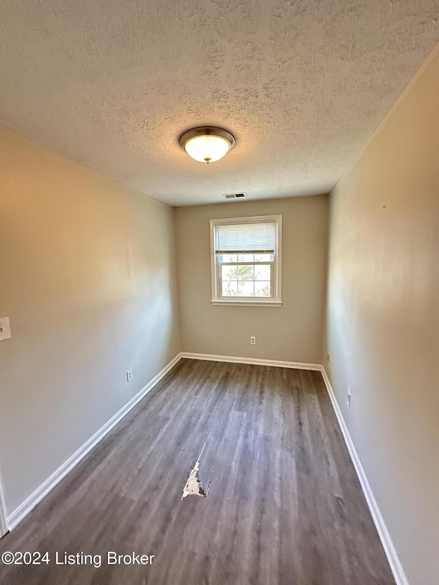 unfurnished room with dark wood-type flooring and a textured ceiling