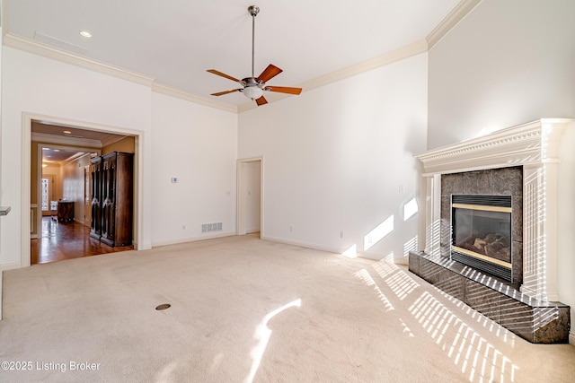 unfurnished living room featuring carpet, ceiling fan, a fireplace, and ornamental molding