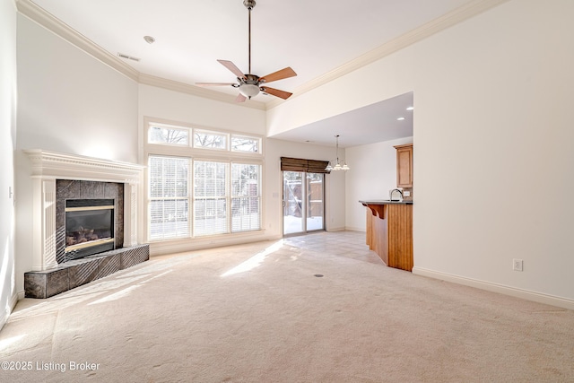 unfurnished living room featuring a fireplace, crown molding, light colored carpet, and ceiling fan