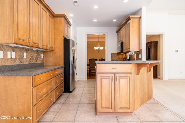 kitchen with a kitchen bar, stainless steel appliances, an inviting chandelier, light tile patterned flooring, and kitchen peninsula