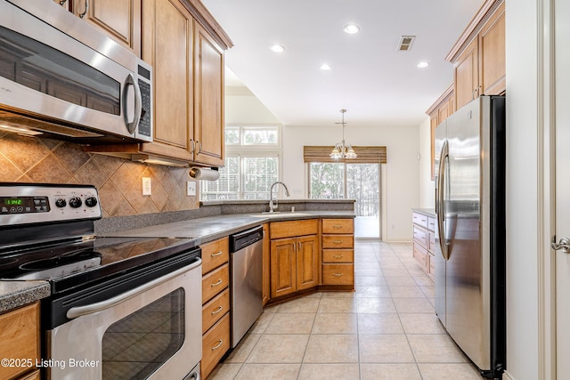 kitchen with light tile patterned flooring, hanging light fixtures, stainless steel appliances, backsplash, and sink