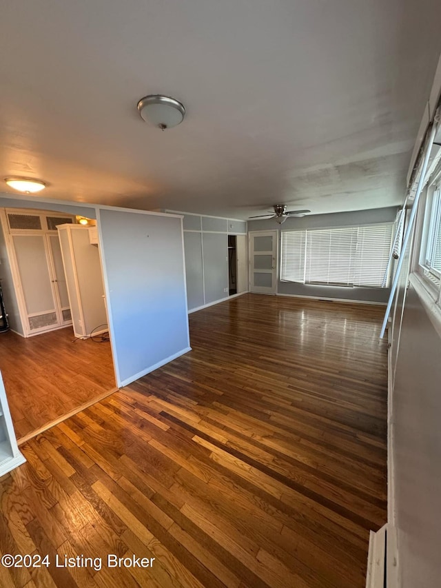 unfurnished living room featuring ceiling fan and dark hardwood / wood-style flooring